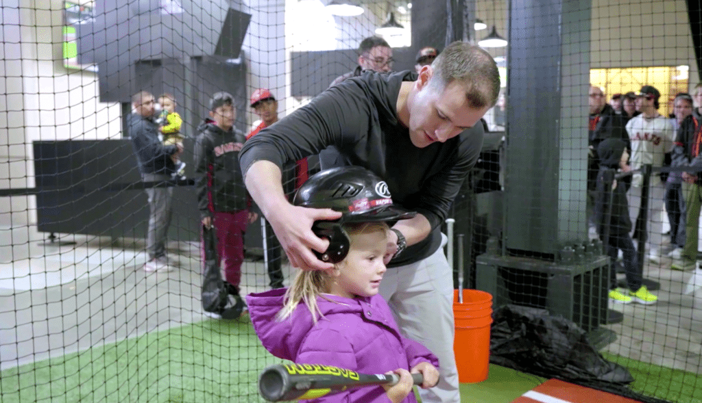 A little girl putting on her helmet to get ready to hit in the HitTrax Suite