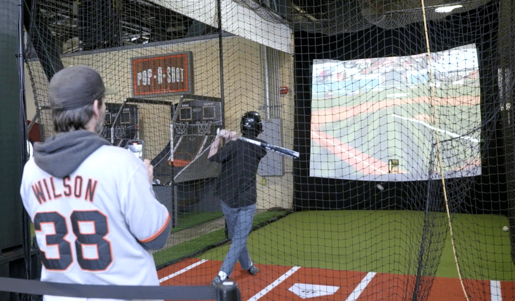 A San Francisco Giants Fan taking video of his friend hitting in the HitTrax Suite